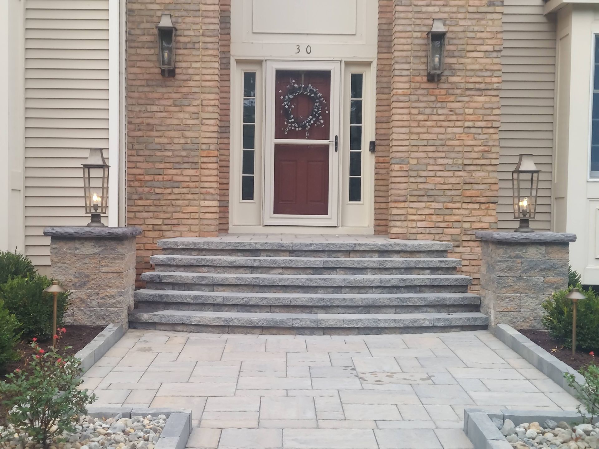 Stone stairs leading up from a paved patio to a grassy lawn, framed by a matching segmental retaining wall. Stone stairs leading up from a paved patio to a grassy lawn, framed by a matching segmental retaining wall.