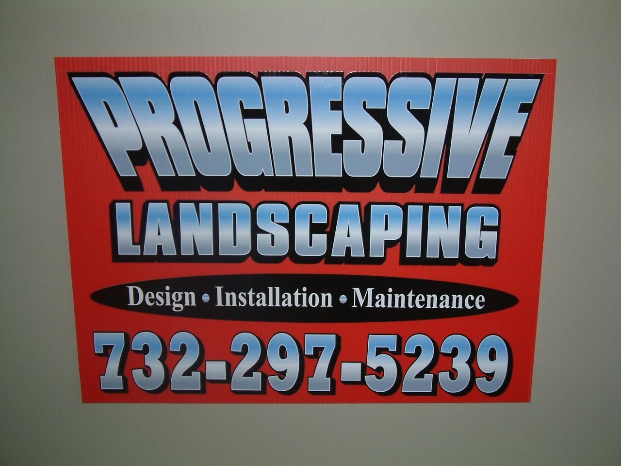 A red sign for Progressive Landscaping listing their services and phone number: 732-297-5239.
