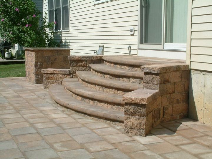 Curved stone steps leading to a sliding glass door on a house with a matching paver patio. Curved stone steps leading to a sliding glass door on a house with a matching paver patio.