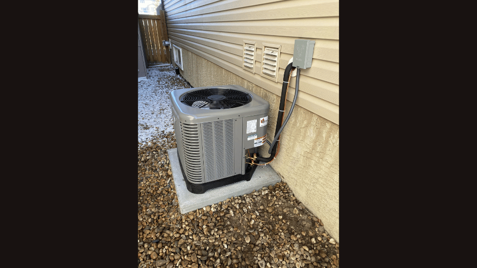 An air conditioner is sitting on the side of a house.