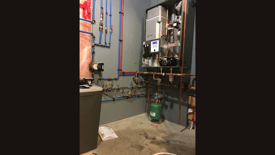 A room with a lot of pipes and a heater in it.
