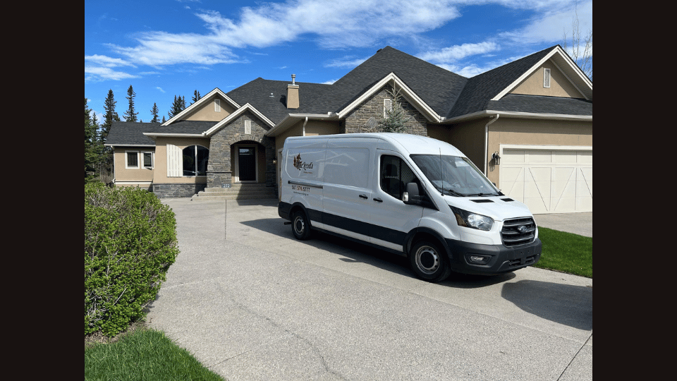 A white van is parked in front of a large house.