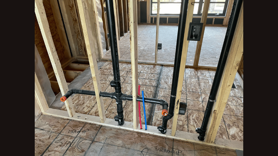 A picture of a house under construction with pipes coming out of the wall.