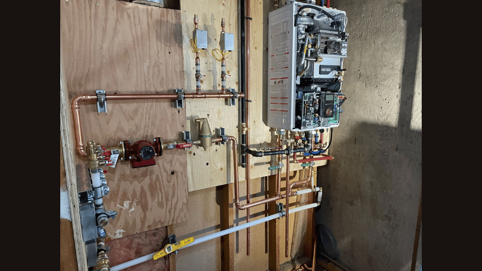 A room with a boiler and pipes on the wall.