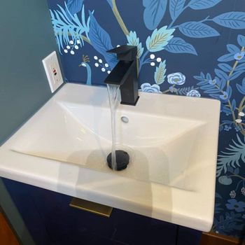 A bathroom sink with a floral wallpaper behind it