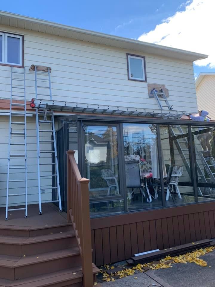 A house with a sunroom and a ladder on the side of it.