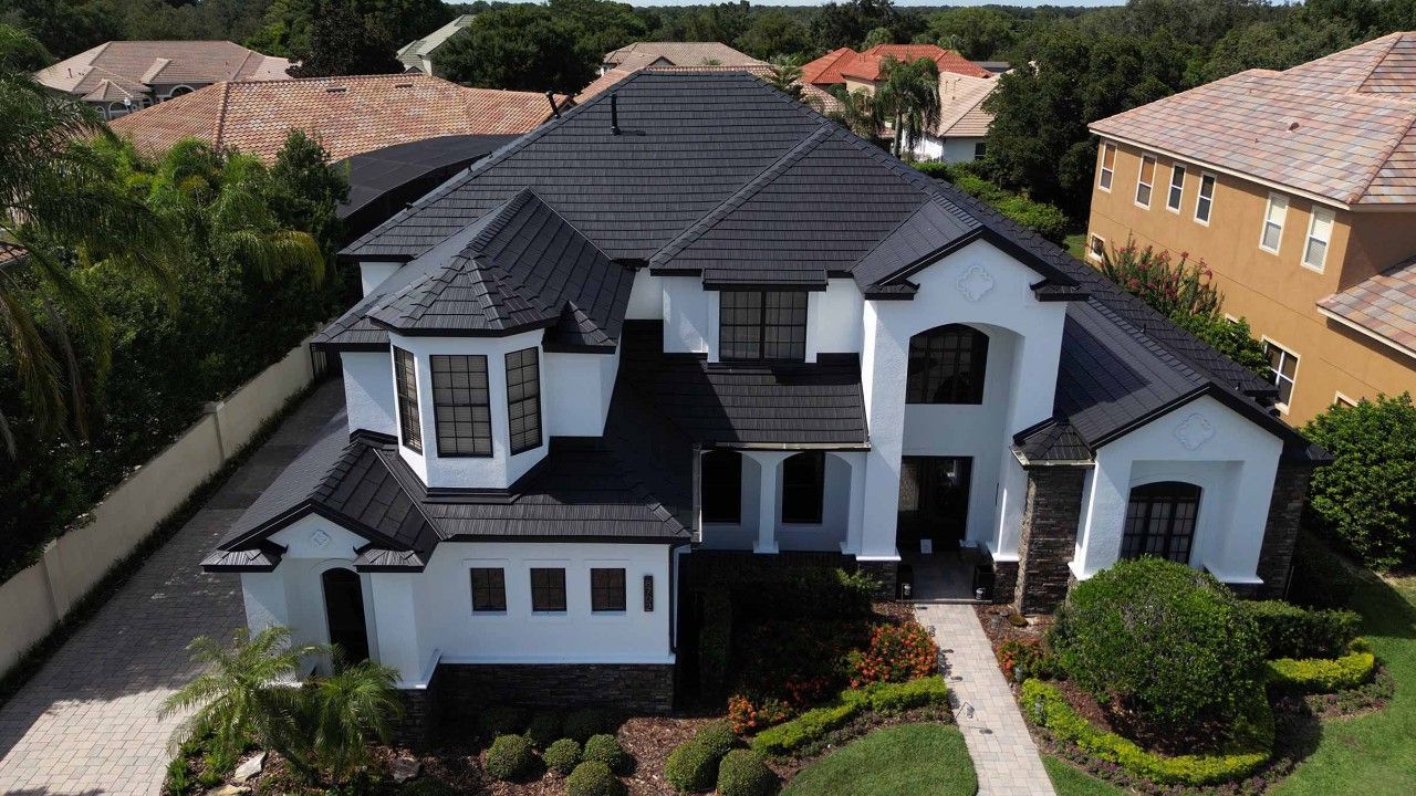 Maison blanche avec toit noir, jardin devant et allée.