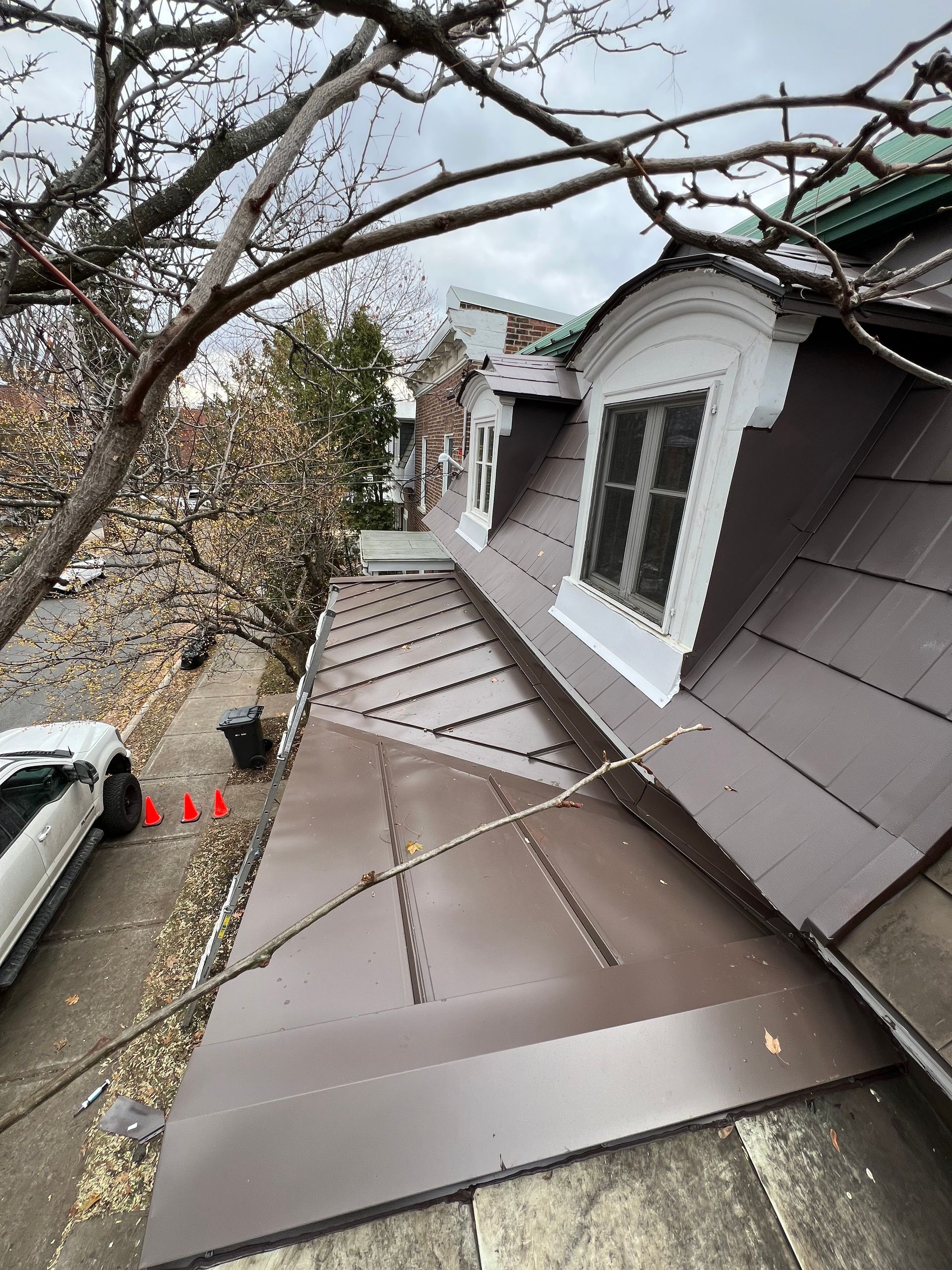 Une voiture blanche est garée sur le côté d'un bâtiment au toit marron.