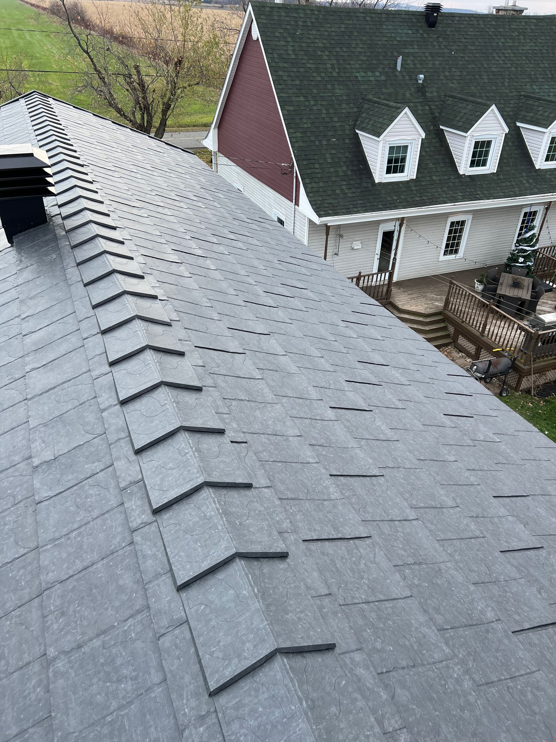 Un toit avec beaucoup de bardeaux et une maison en arrière-plan.