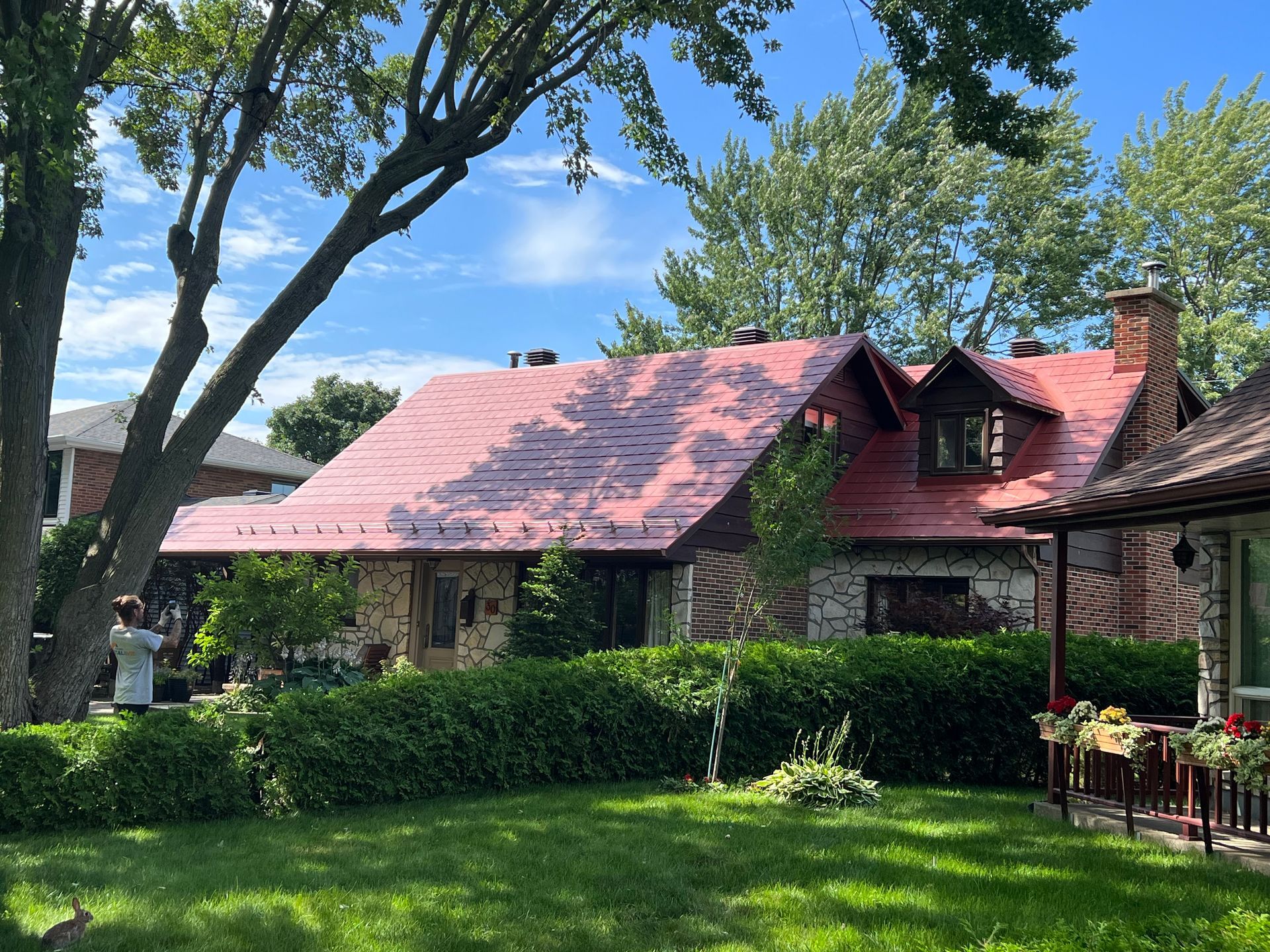 Un homme se tient devant une maison au toit rouge.