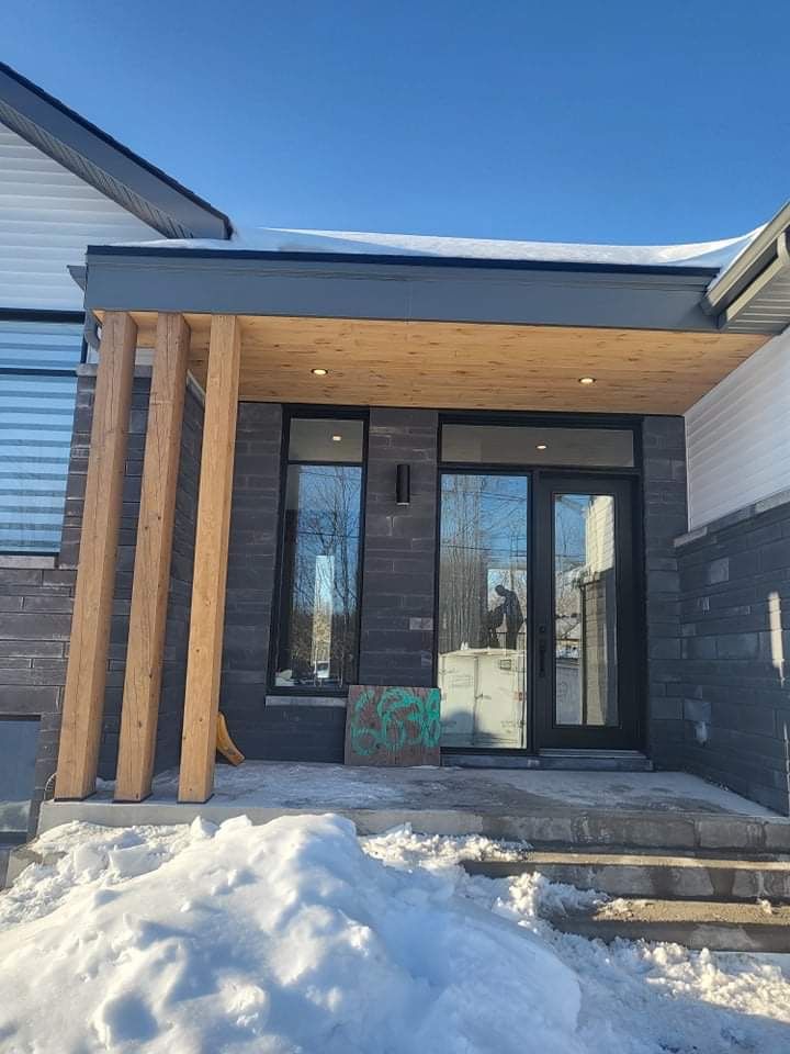 Une maison avec un porche et des escaliers dans la neige.