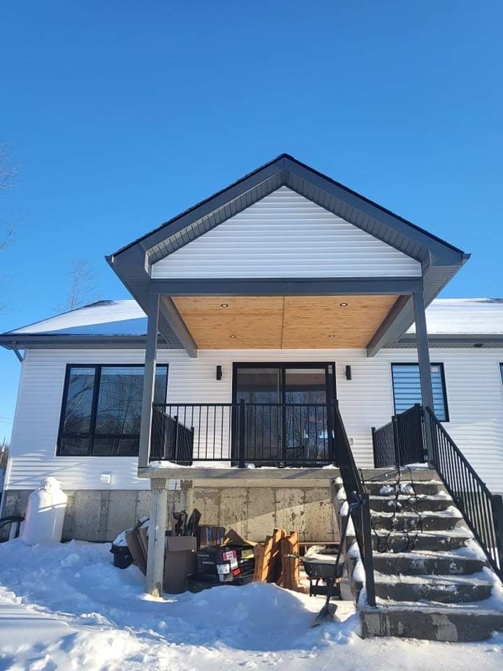Une maison blanche avec un porche et des escaliers dans la neige.