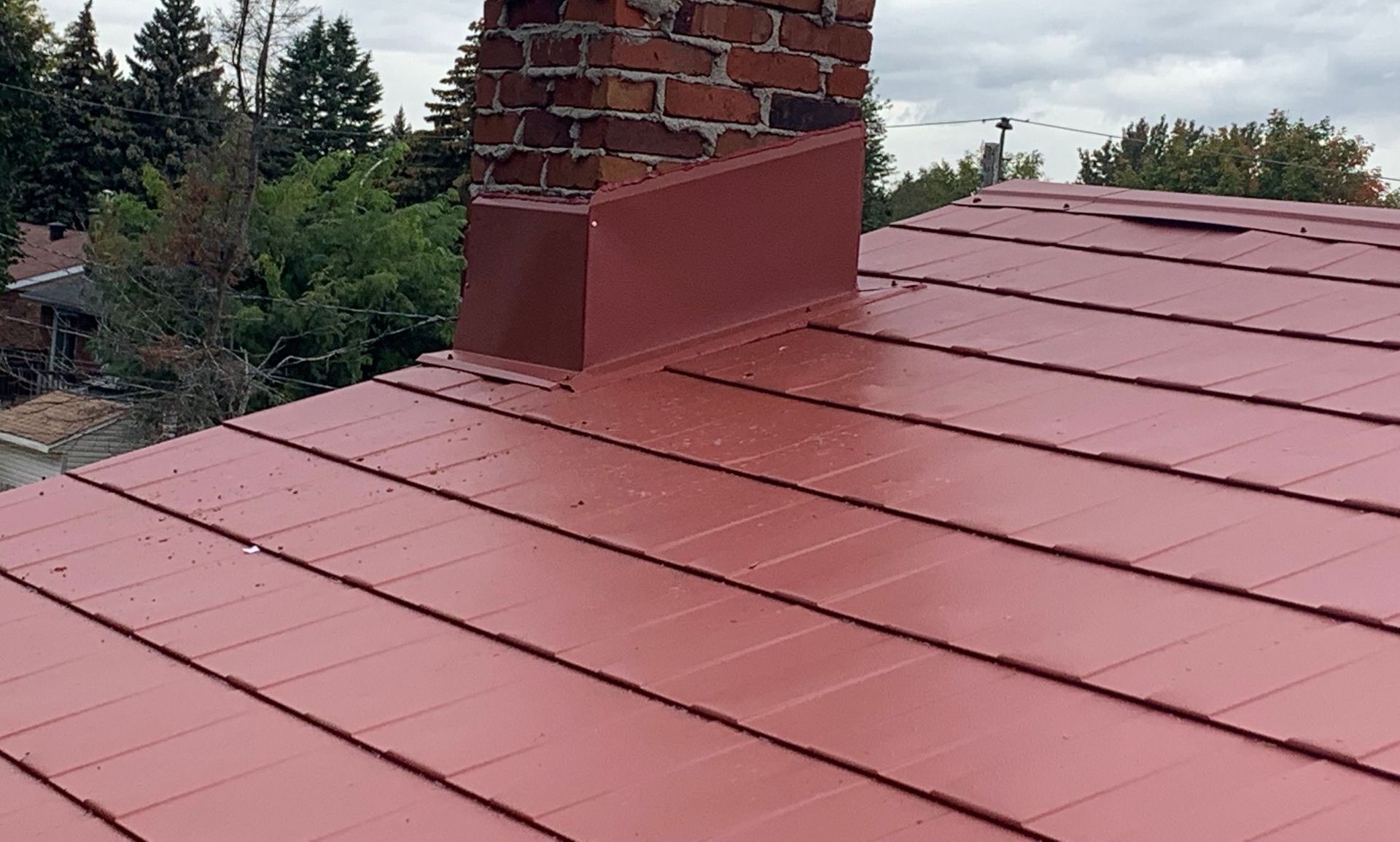 Un toit rouge avec une cheminée au-dessus.