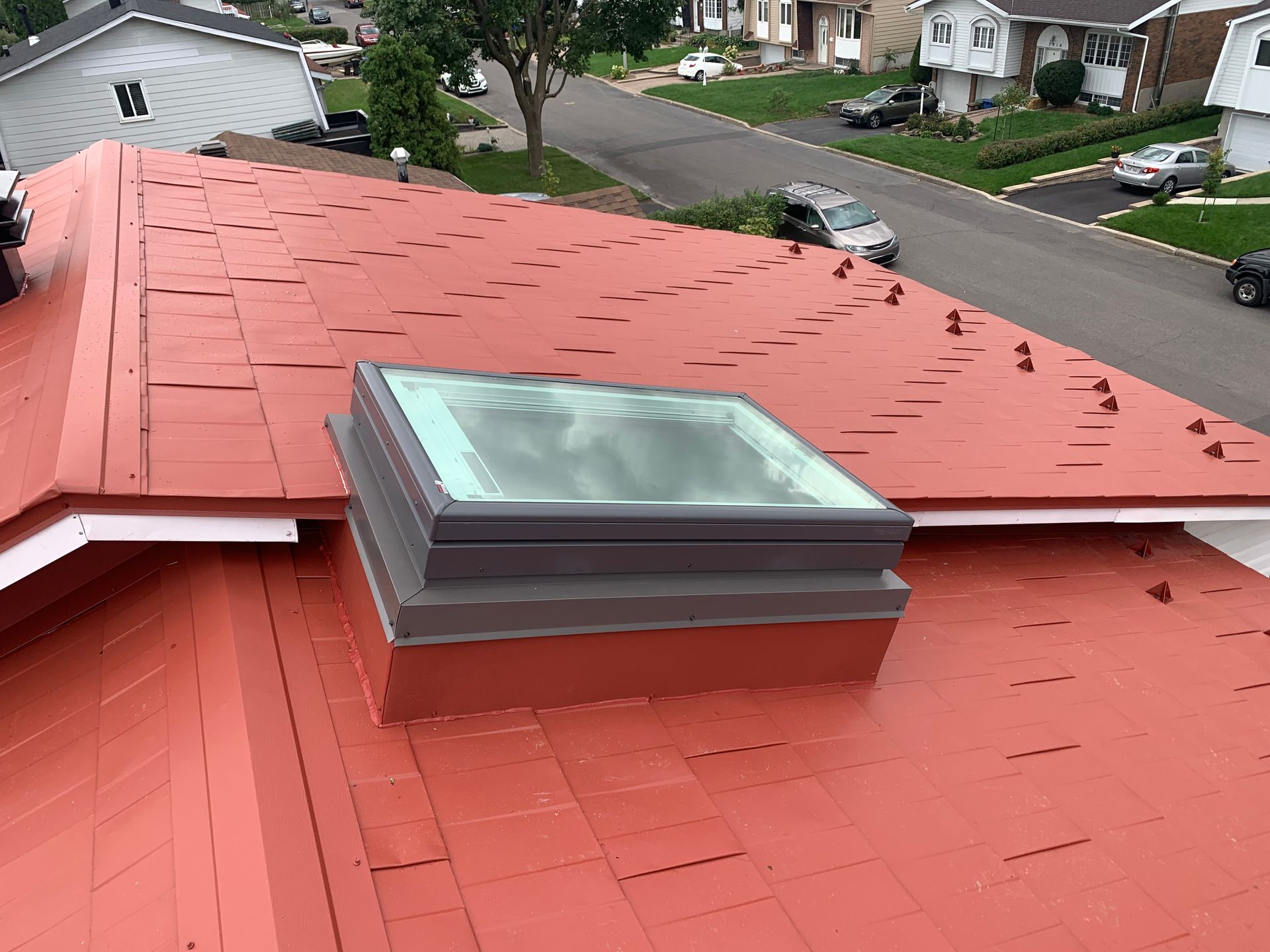 Un toit rouge avec une lucarne au-dessus.