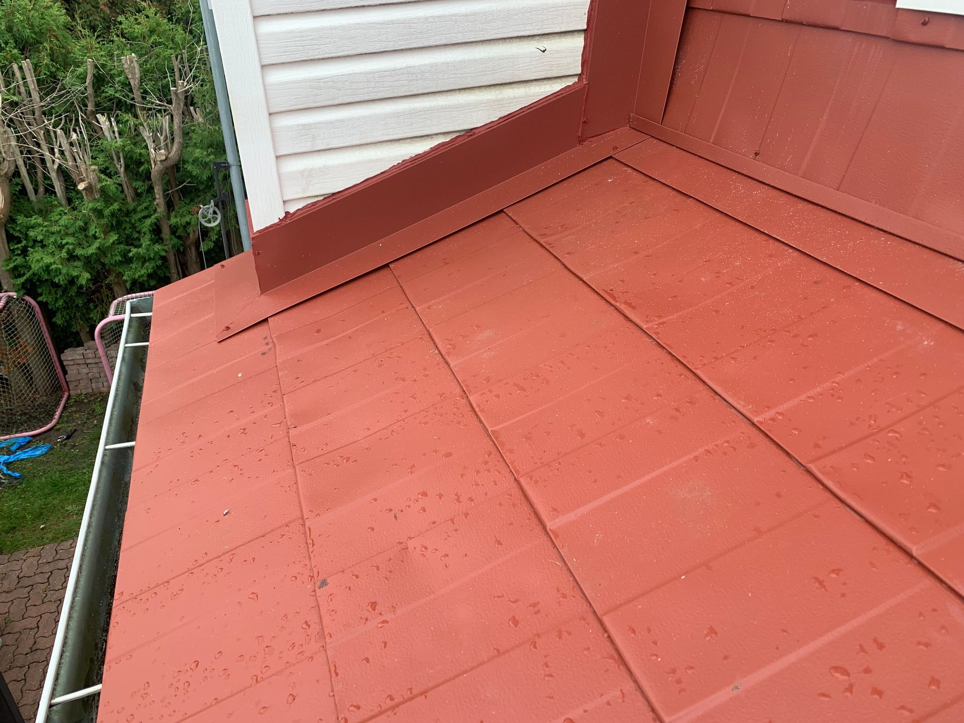 Un toit rouge avec une maison blanche en arrière-plan.