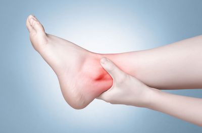 Woman Massaging Her Painful Ankle — Glenview, IL — Dr. Ron Riegelhaupt and Associates