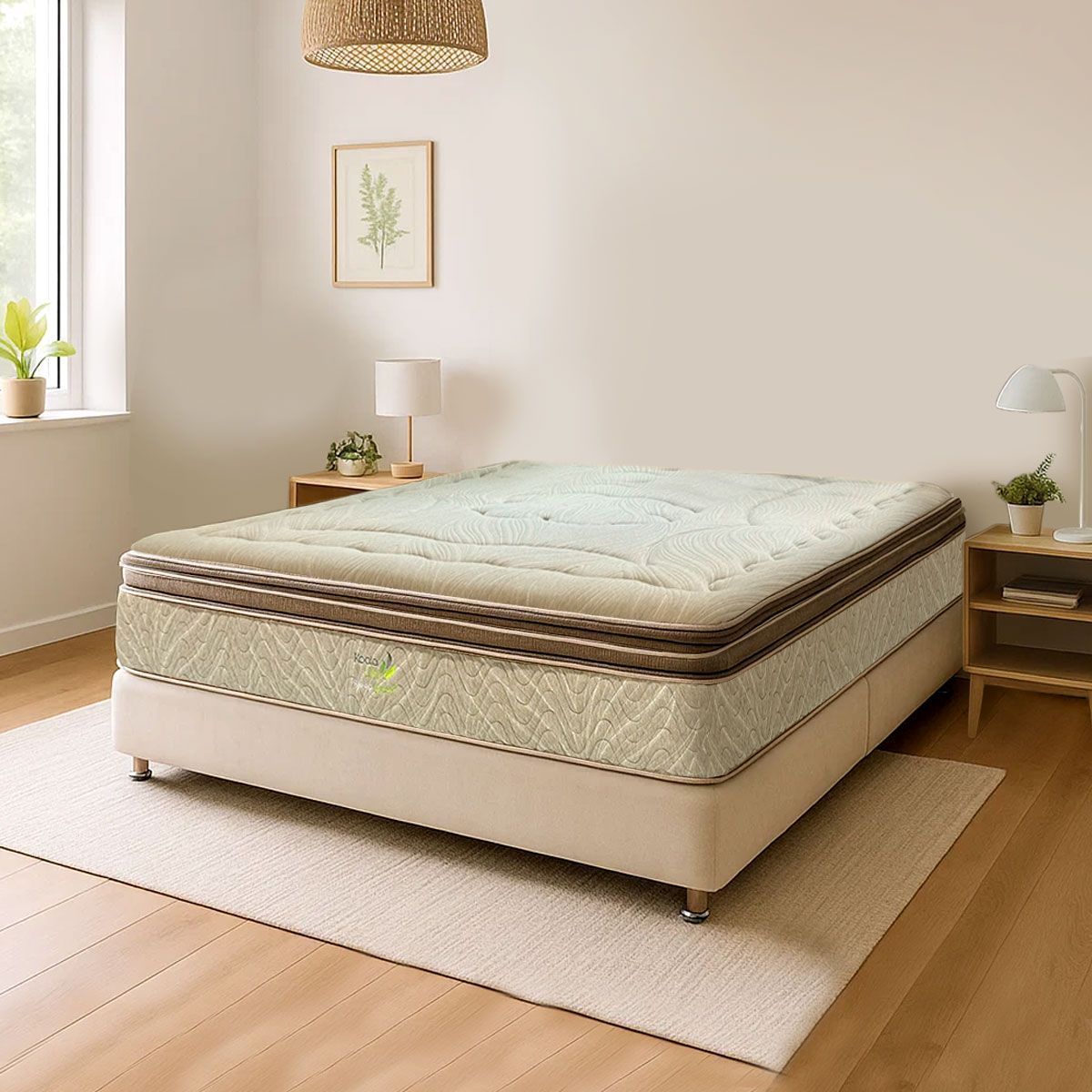 Colchón beige sobre la estructura de una cama en un dormitorio luminoso. Cerca hay mesitas de noche con lámparas y plantas.