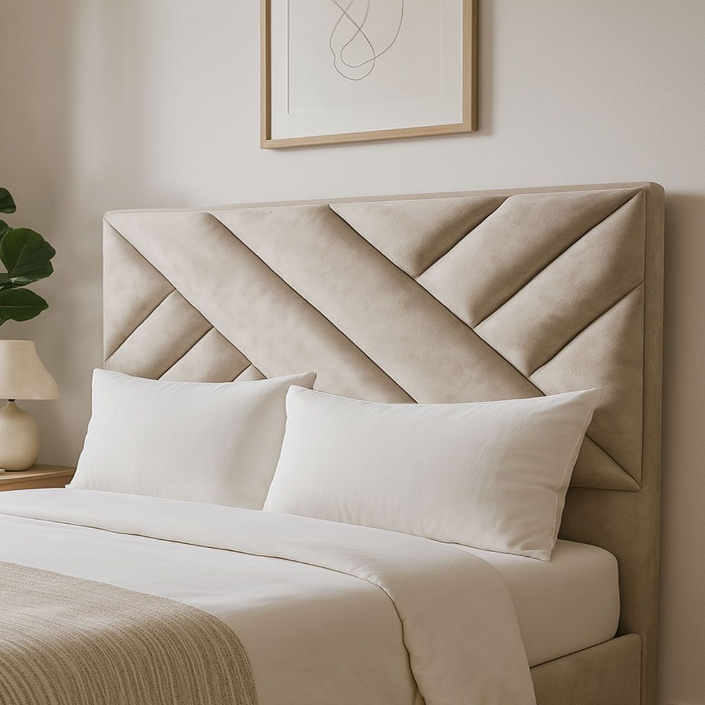 Una cama tapizada en color beige con cabecero geométrico de paneles, decorada con almohadas blancas y una manta texturizada.