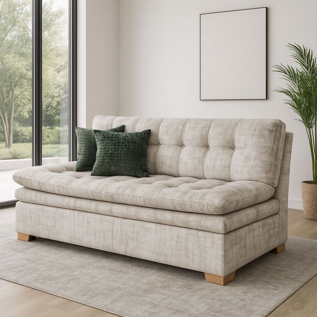 En una habitación luminosa y moderna, un sofá capitoné de color claro con dos cojines decorativos de color verde oscuro se encuentra sobre una alfombra gris.