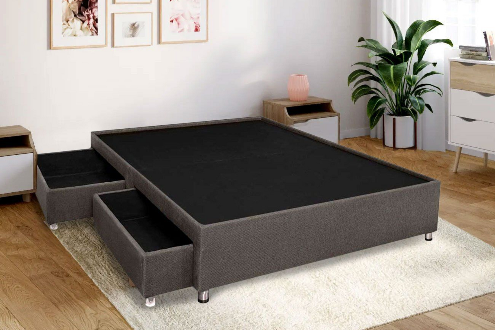Una estructura de cama tapizada en gris oscuro con dos cajones extraíbles sobre una alfombra clara en un dormitorio luminoso.