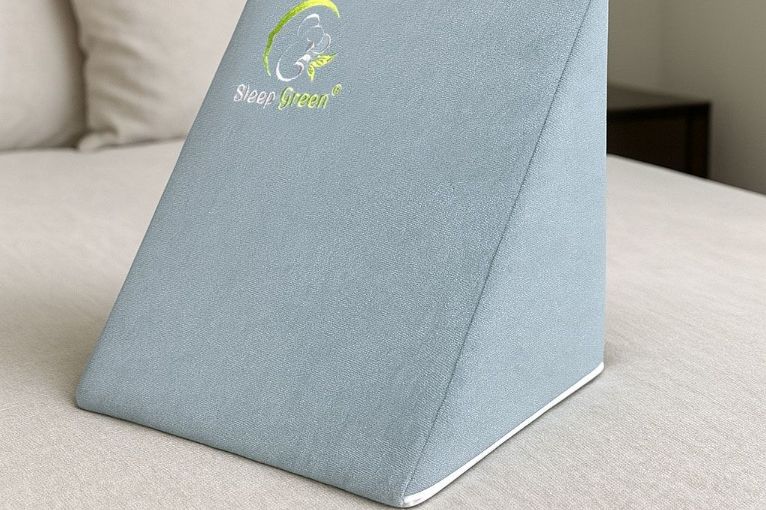 Almohada de cuña azul sobre una cama, con el logotipo 