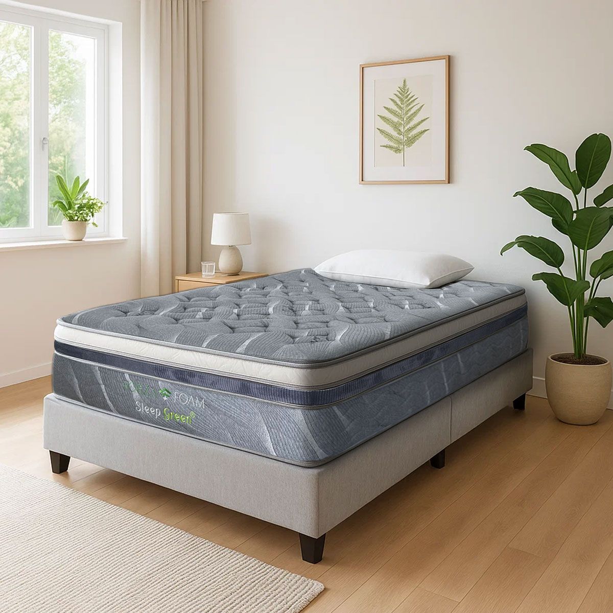 Un colchón acolchado de color gris descansa sobre una estructura de cama tapizada a juego en un dormitorio luminoso y moderno, decorado con una planta y obras de arte.