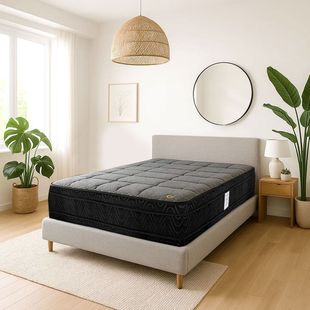 Habitación luminosa con cama negra, lámpara colgante de mimbre, espejo redondo y plantas en macetas sobre una alfombra.