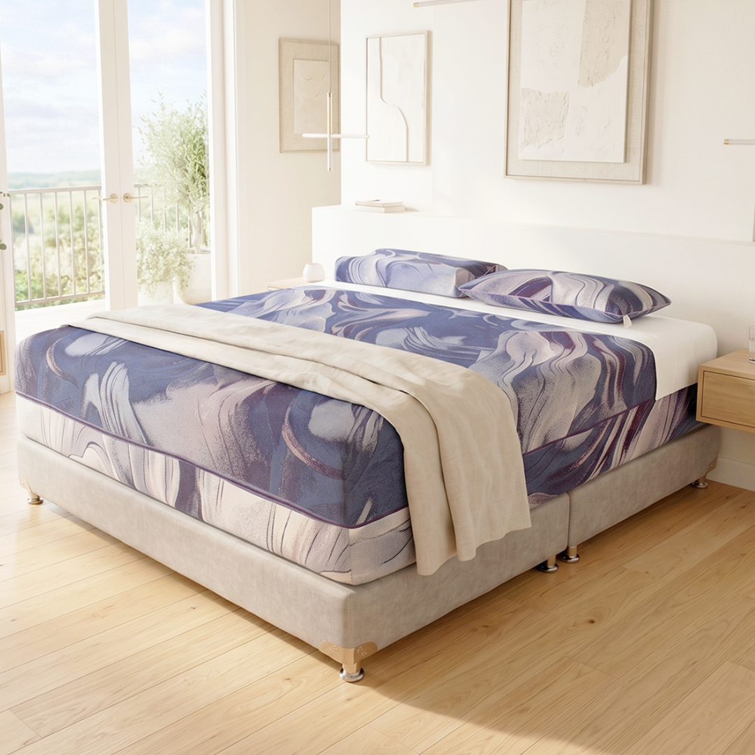 Habitación luminosa con cama hecha, ropa de cama con estampado azul y grandes ventanales que dejan entrar la luz del sol.