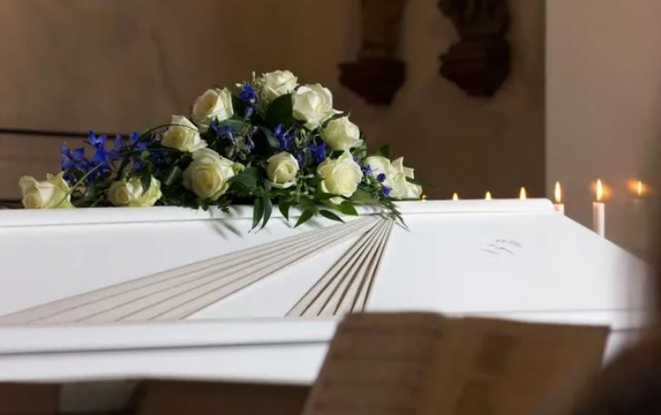 Close Up Shot of Modest Flower Arrangement on a White Coffin