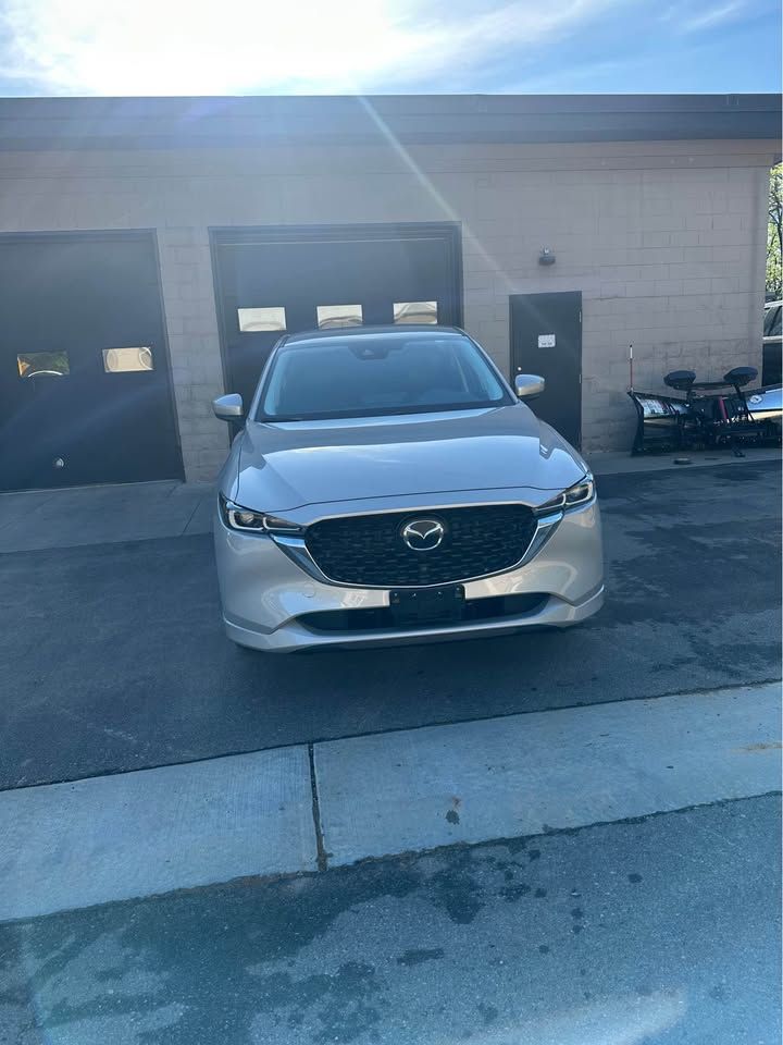 A silver mazda cx 5 is parked in front of a garage.