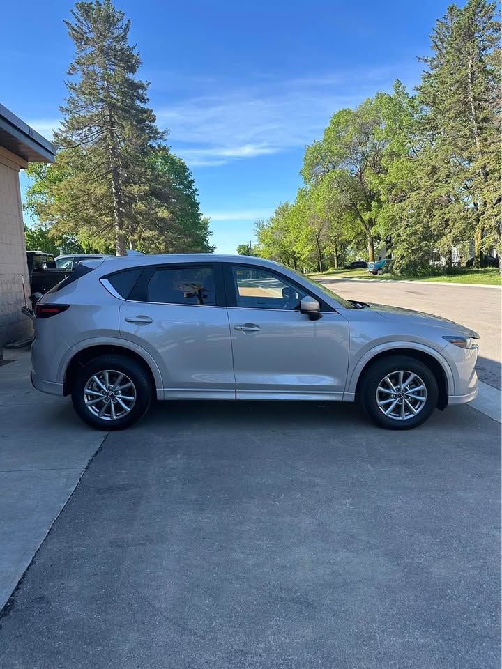 A silver mazda cx-5 is parked in a driveway next to a house.