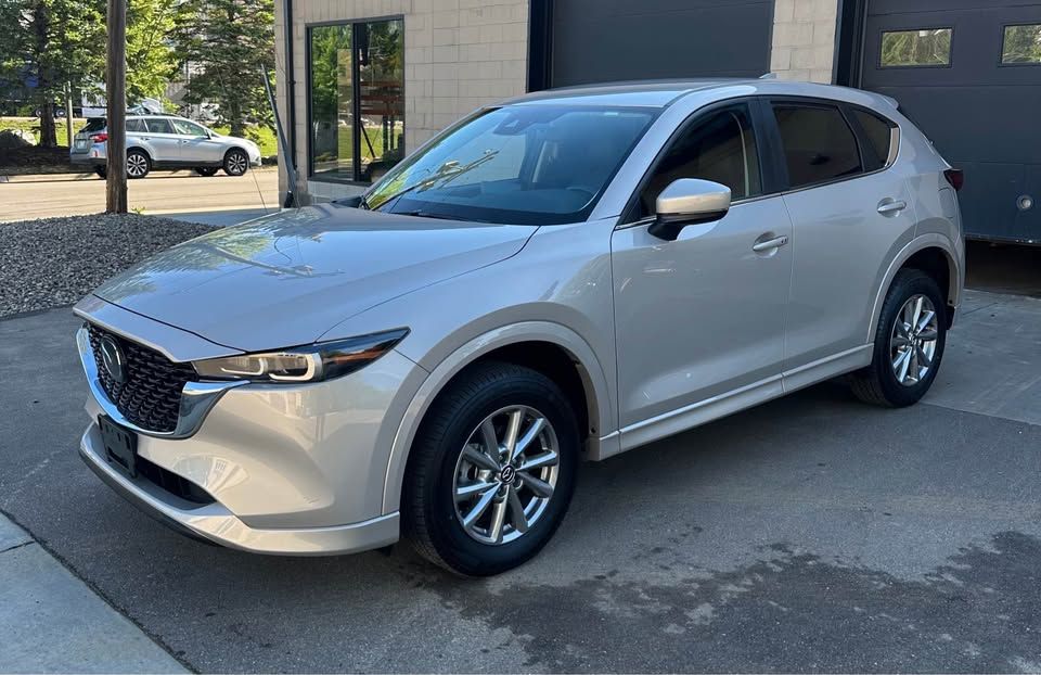 A silver mazda cx-5 is parked in front of a building.