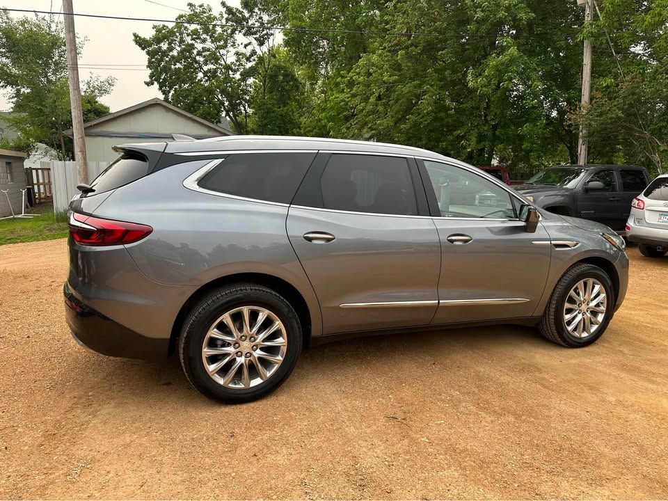 A gray suv is parked in a dirt lot in front of a house.