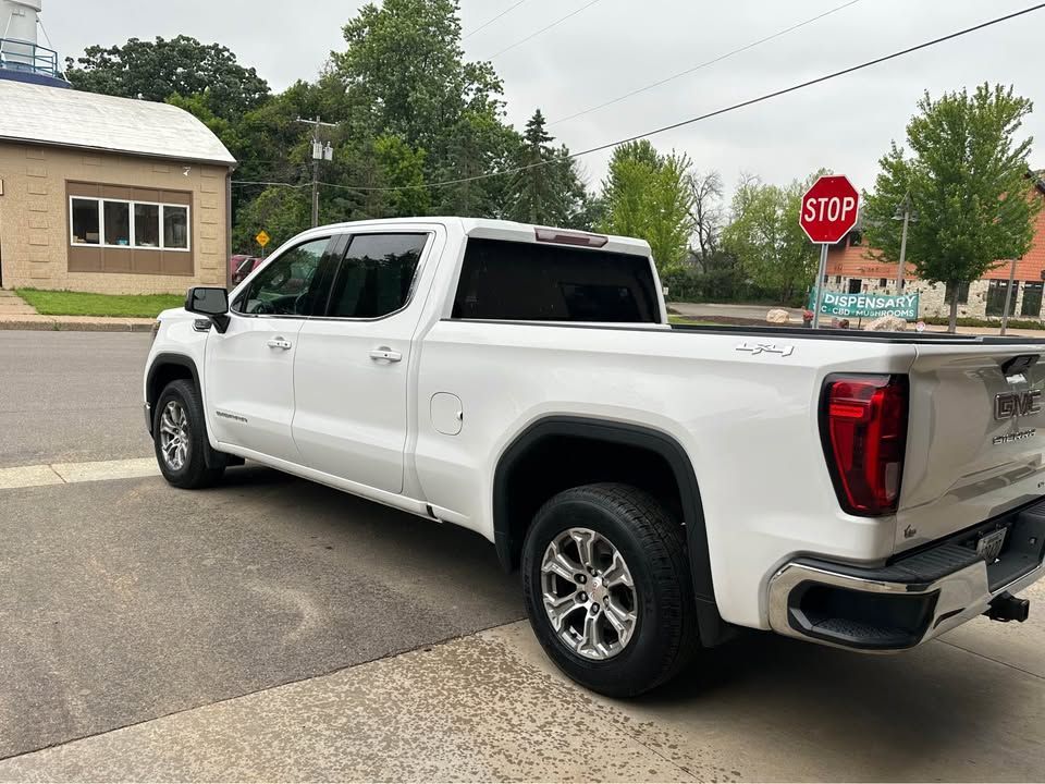 A white truck is parked on the side of the road next to a stop sign.