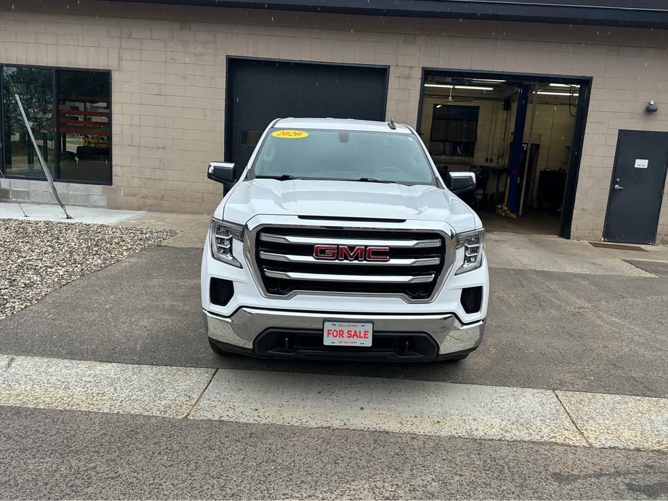 A white gmc sierra is parked in front of a building.