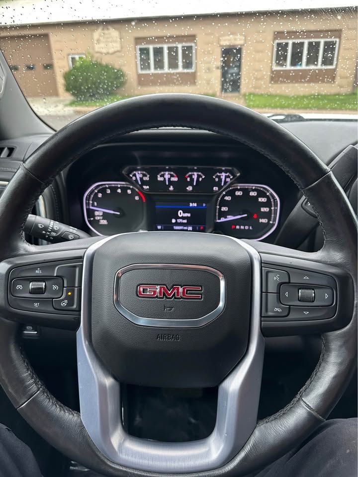 A person is sitting in the driver 's seat of a gmc truck.