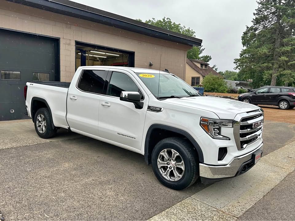 A white pickup truck is parked in front of a garage.
