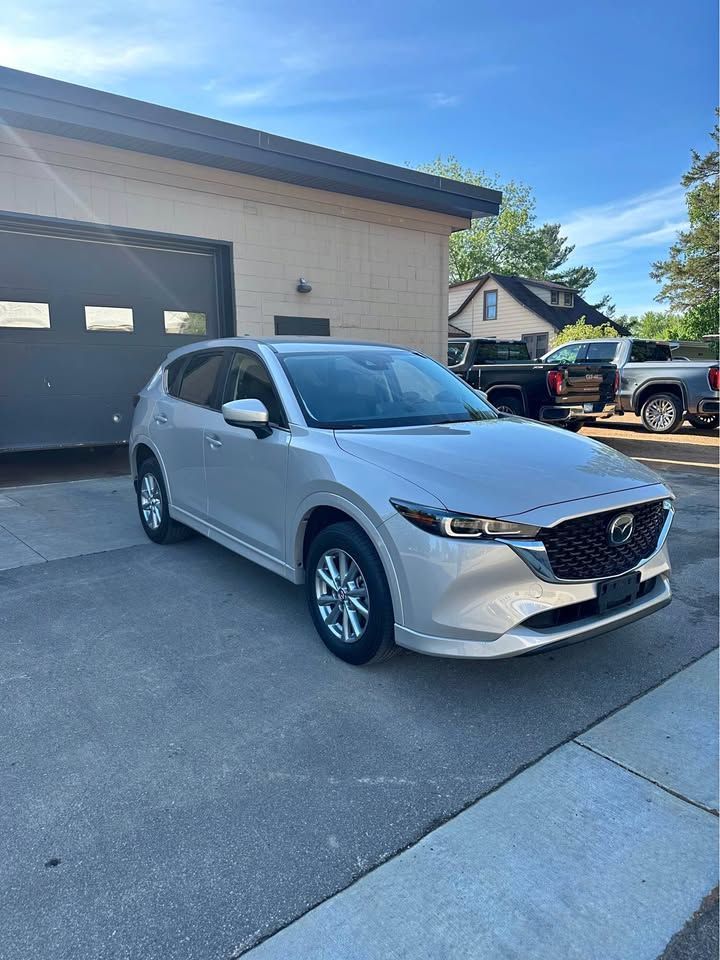 A silver mazda cx-5 is parked in front of a garage.