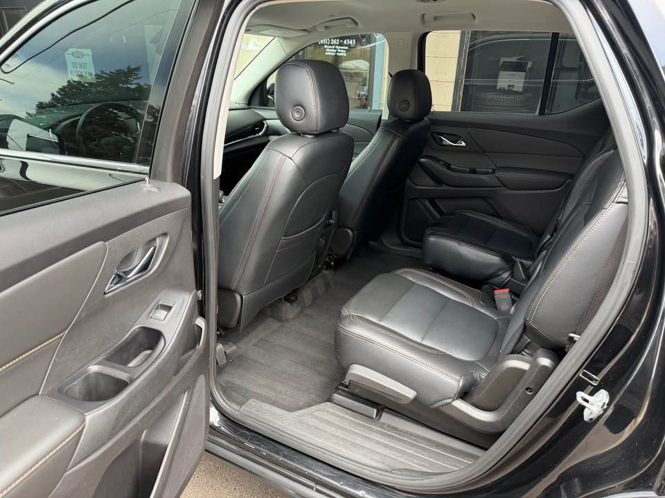 Black SUV interior with black leather seats, including the front seats and second row. The back door is open.