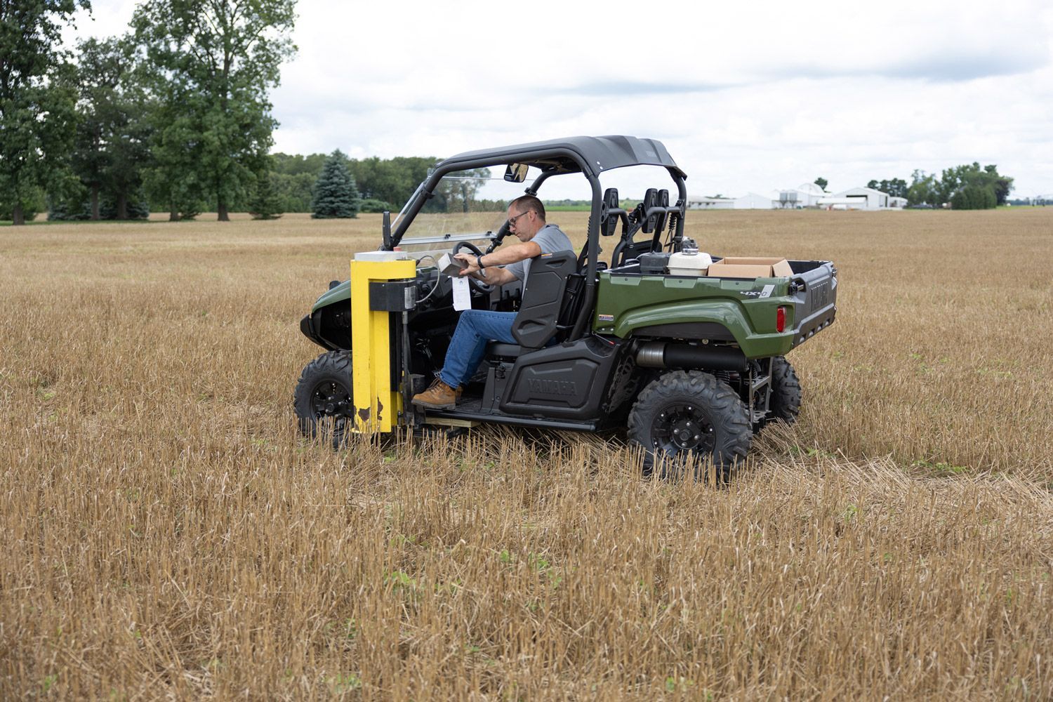 A man is driving a green atv in a field.