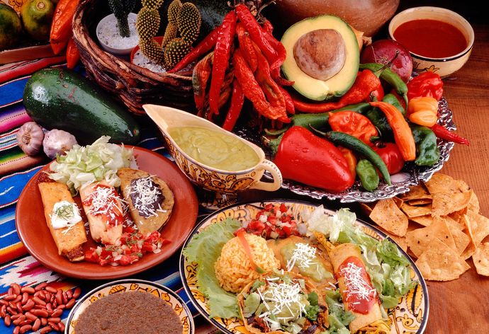 Una mesa cubierta con platos de comida mexicana y verduras.