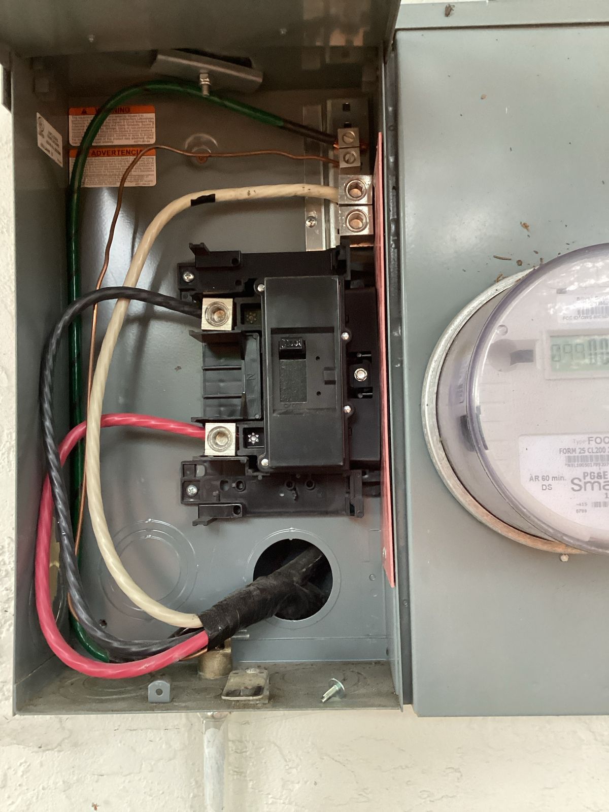 Electrical panel with wires and circuit breaker. Gray metal box near a meter.