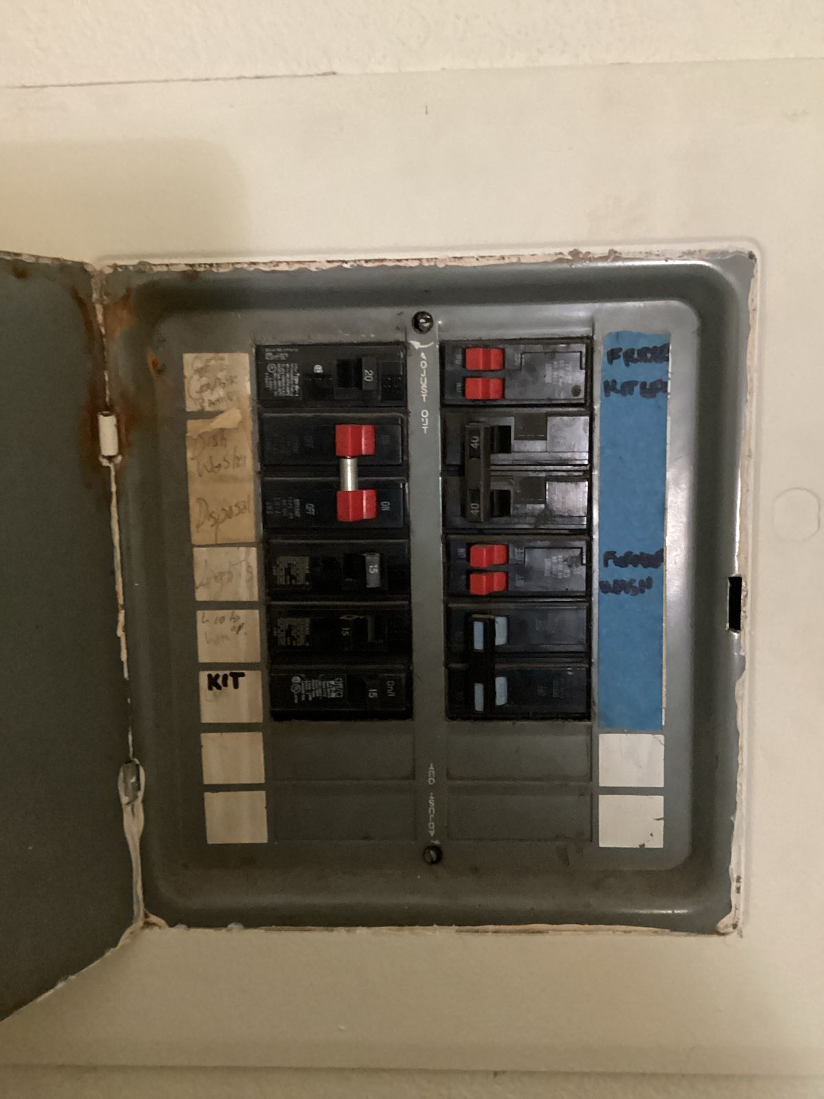An open electrical breaker box on a wall, with visible switches and labels.