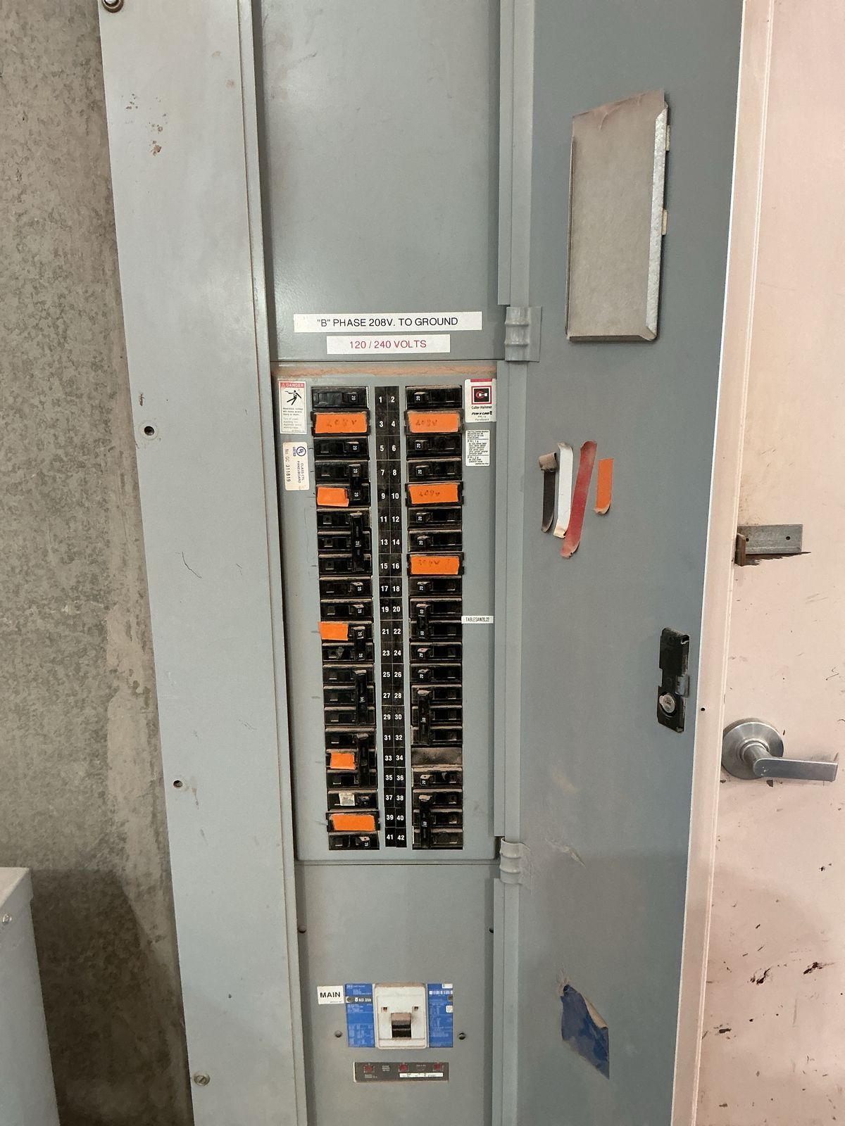 Electrical panel with multiple circuit breakers, mounted in a metal cabinet, located indoors.