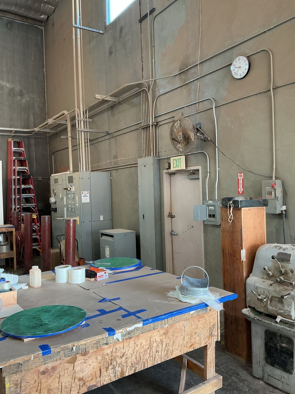 Workshop interior with electrical conduits, breaker boxes, workbench, and equipment.