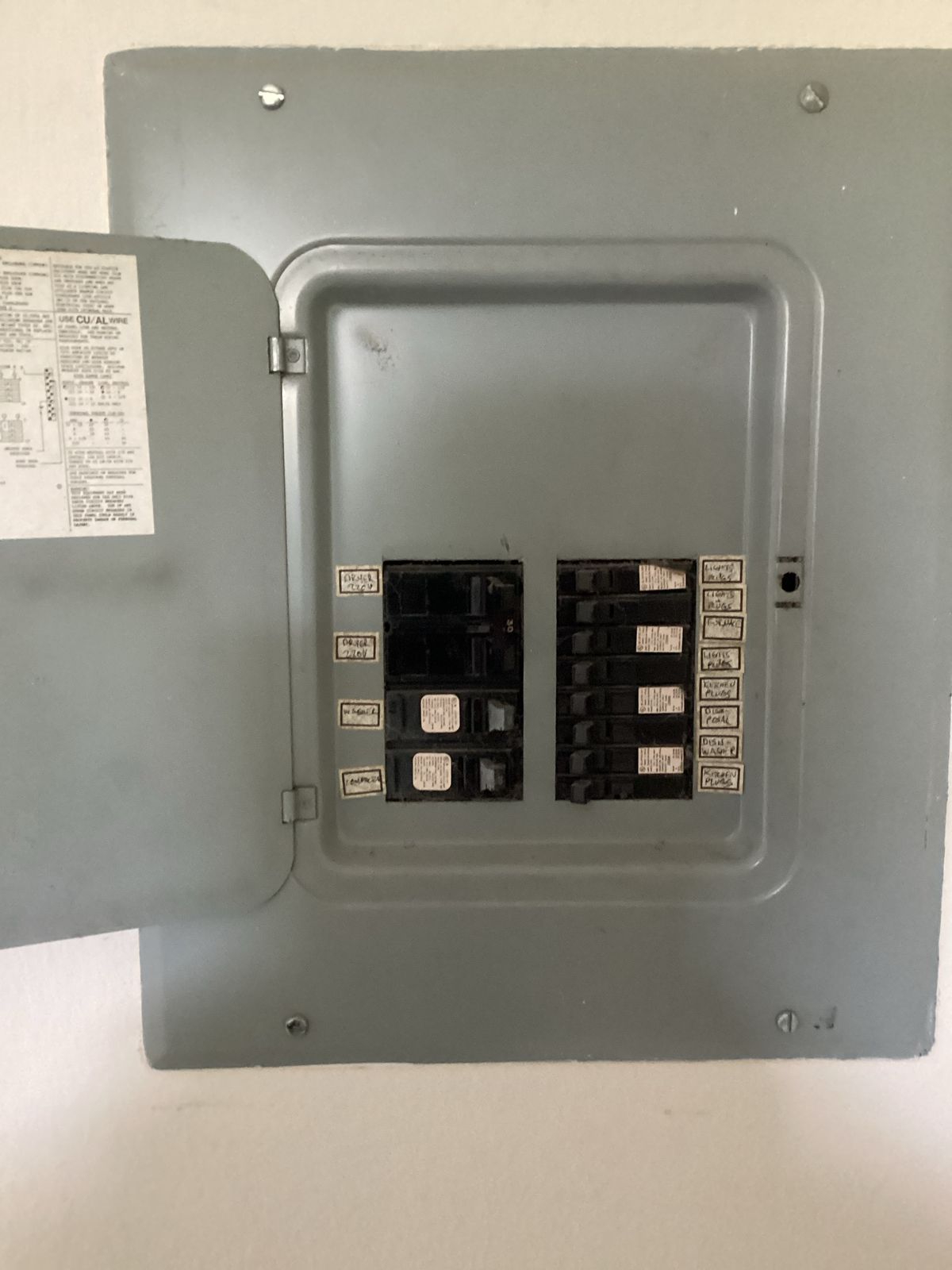 Open gray electrical panel with circuit breakers.