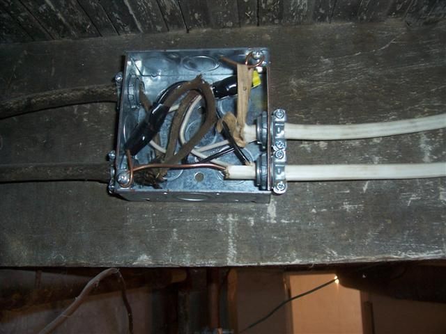 Metal electrical junction box with wires connected on a wooden beam.