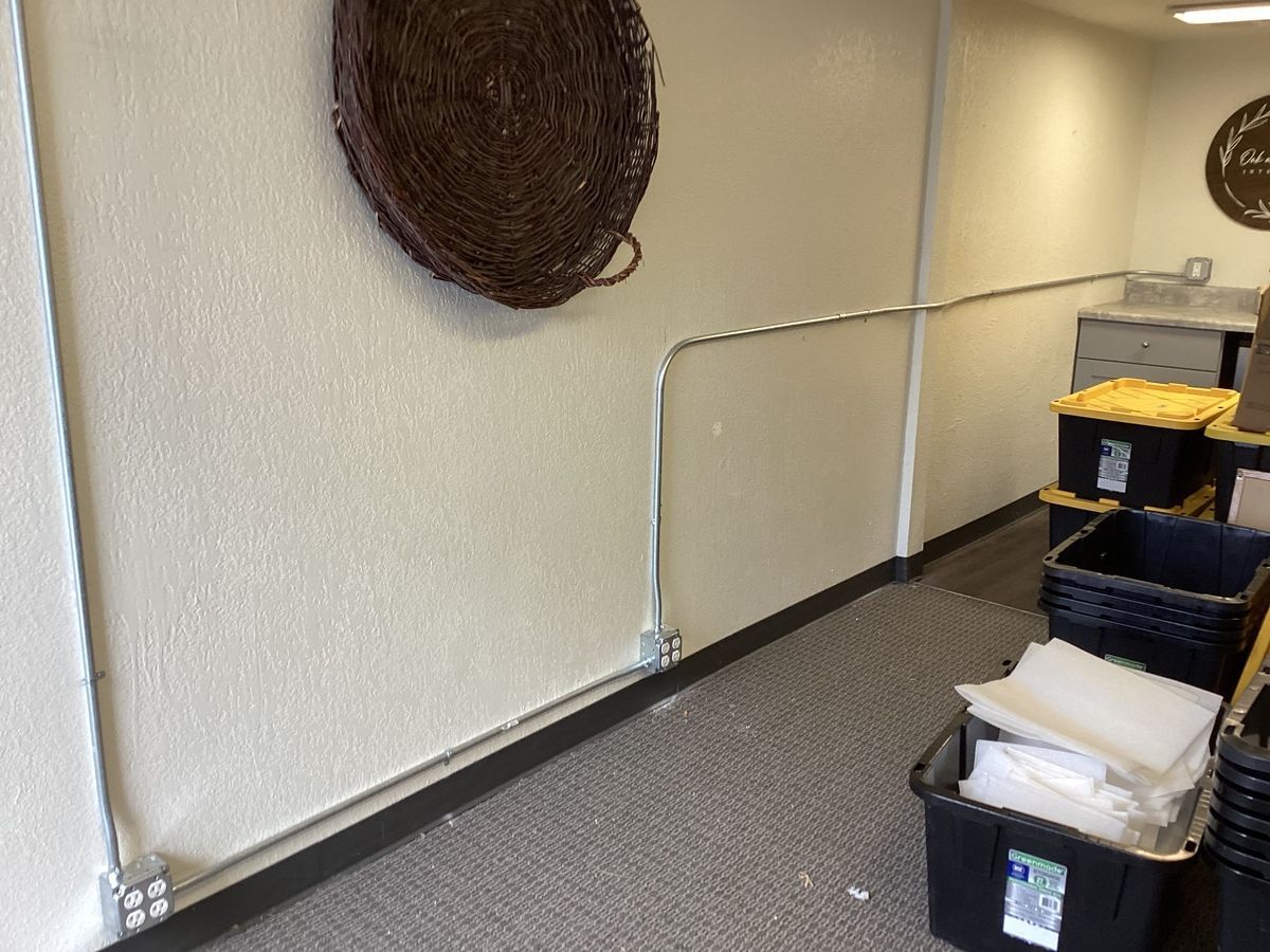 Interior with a wall-mounted basket and electrical conduit. Bins and equipment line the right side.