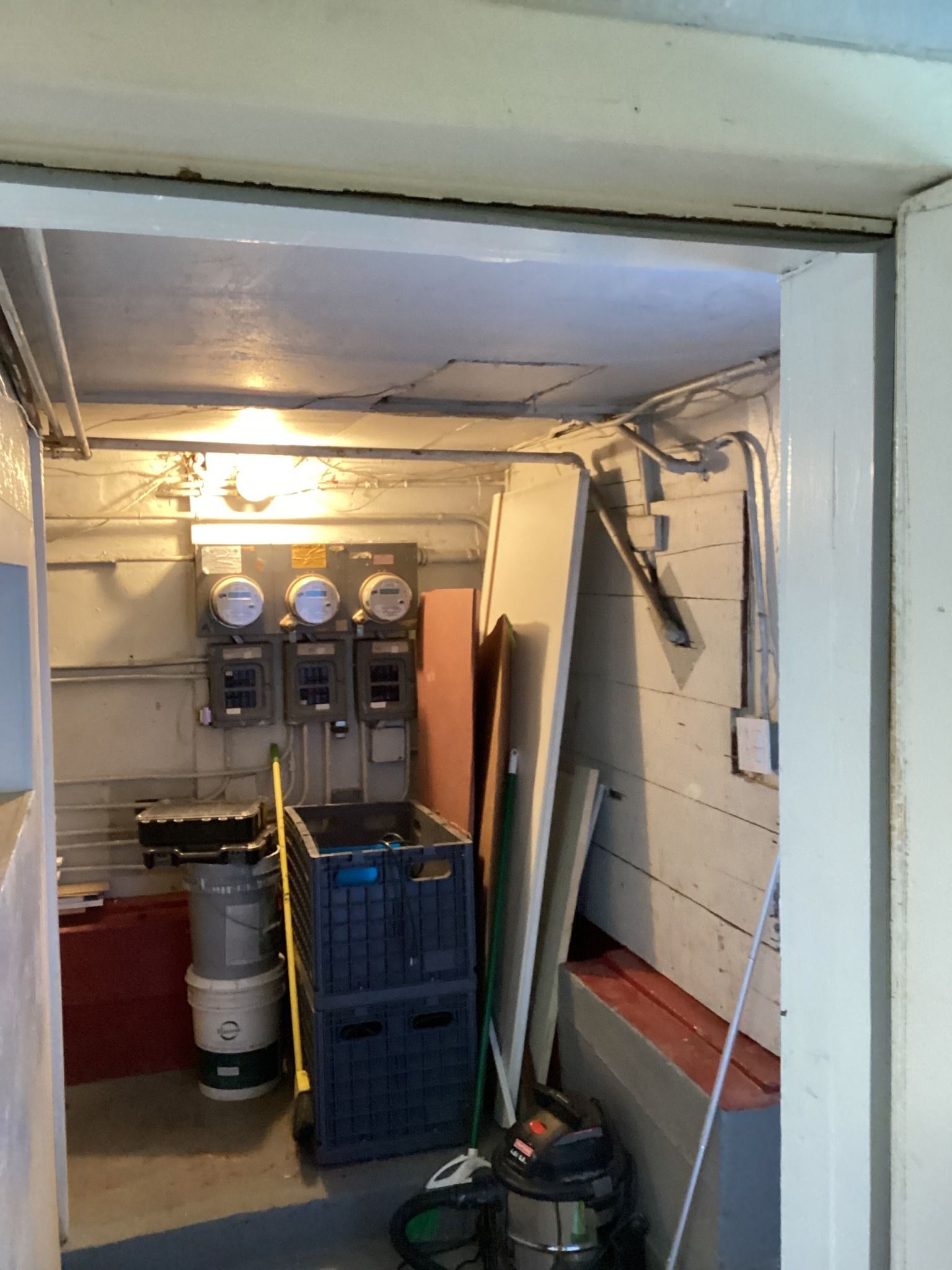 Interior utility room with electrical meters, storage crates, and equipment.