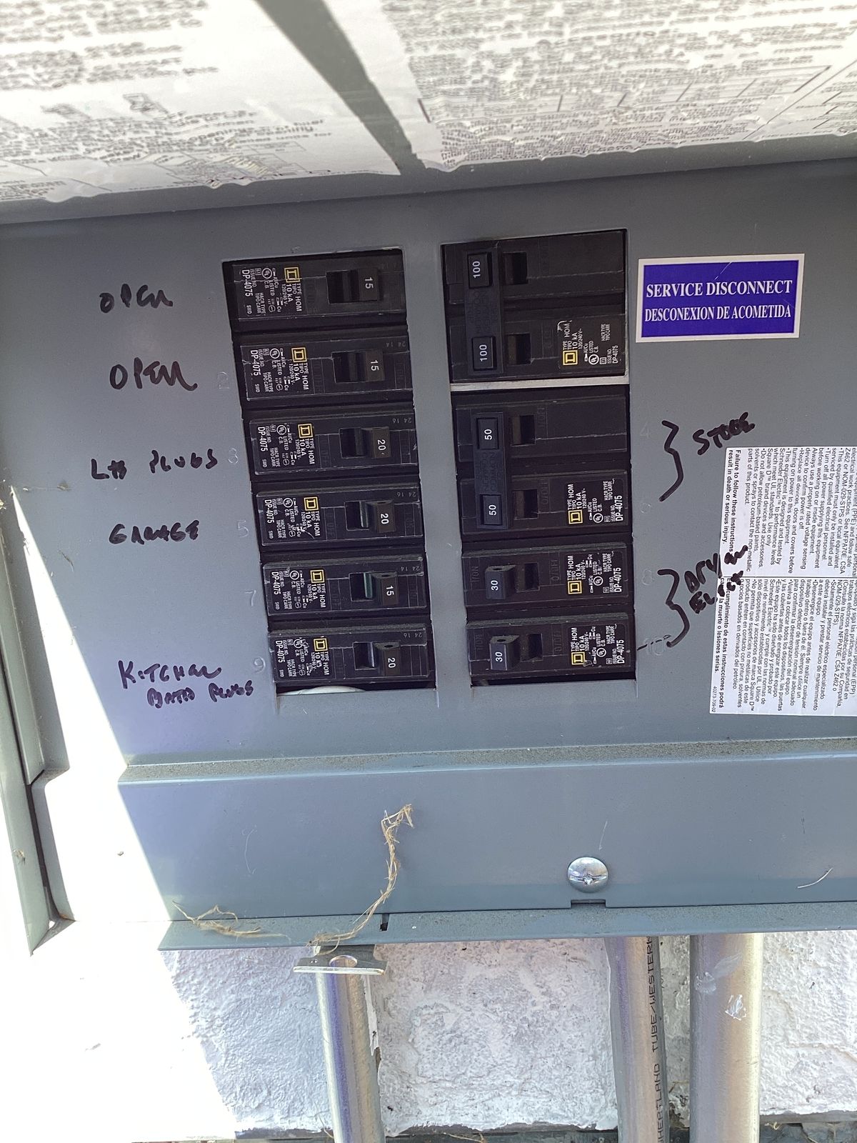 Gray electrical panel with labeled circuit breakers. Handwritten labels include 